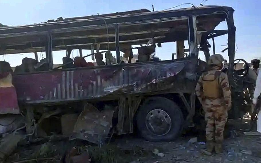 A paramilitary soldier examines a damaged bus 