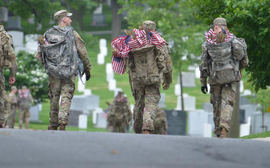 A group of soldiers place flags at gravesites at Arlington National Cemetery