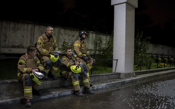 Firefighters rest on a curb during after responding to a Russian attack that killed a teenager in Kyiv, Ukraine, early Saturday, Oct. 26, 2024. (AP Photo/Alex Babenko)