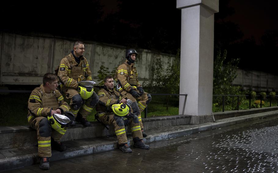 Firefighters rest on a curb after responding to a Russian attack in Kyiv.