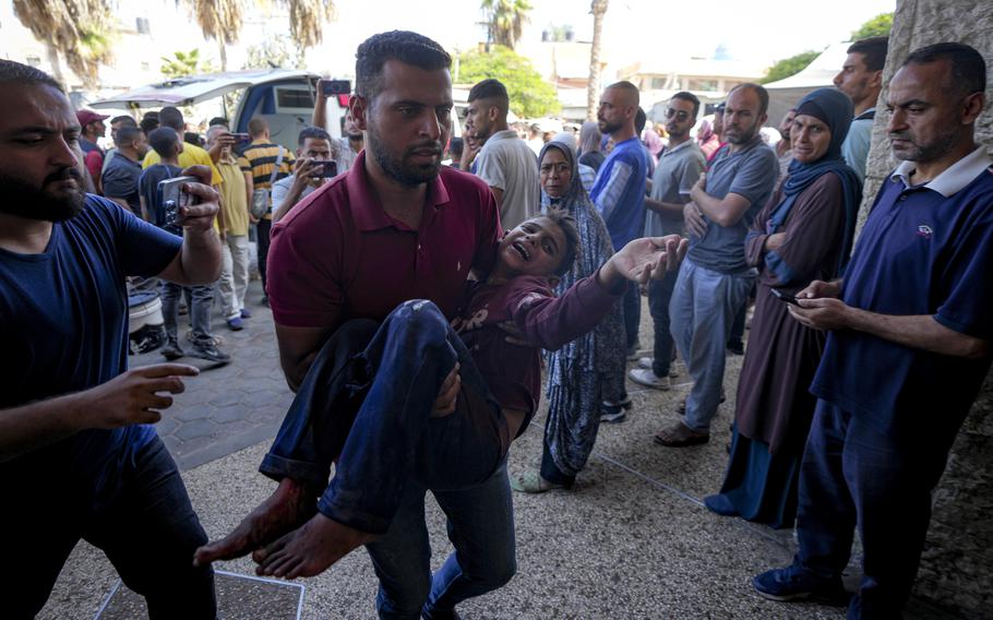 A Palestinian man carries an injured child after an Israeli airstrike in Deir al Balah, Gaza Strip.