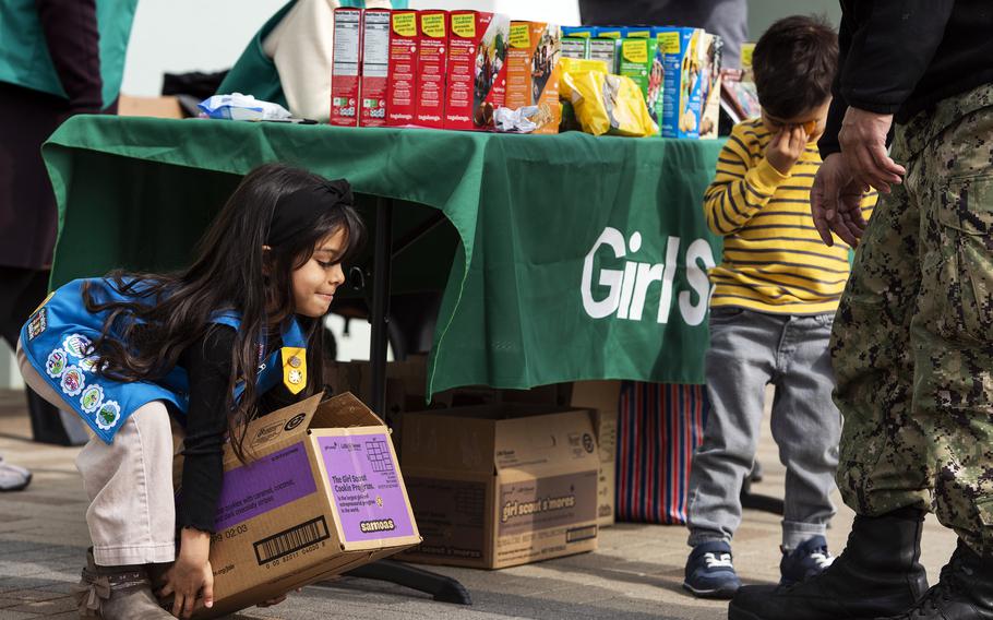 Daisy Girl Scout Ariyah Aguirre, 6, lifts a box of cookies outside the commissary at Marine Corps Air Station Iwakuni, Japan, in February 2023.