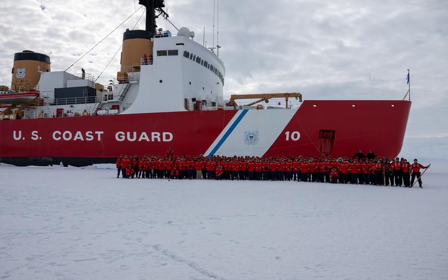 The crew poses for a photo in front of the ship.