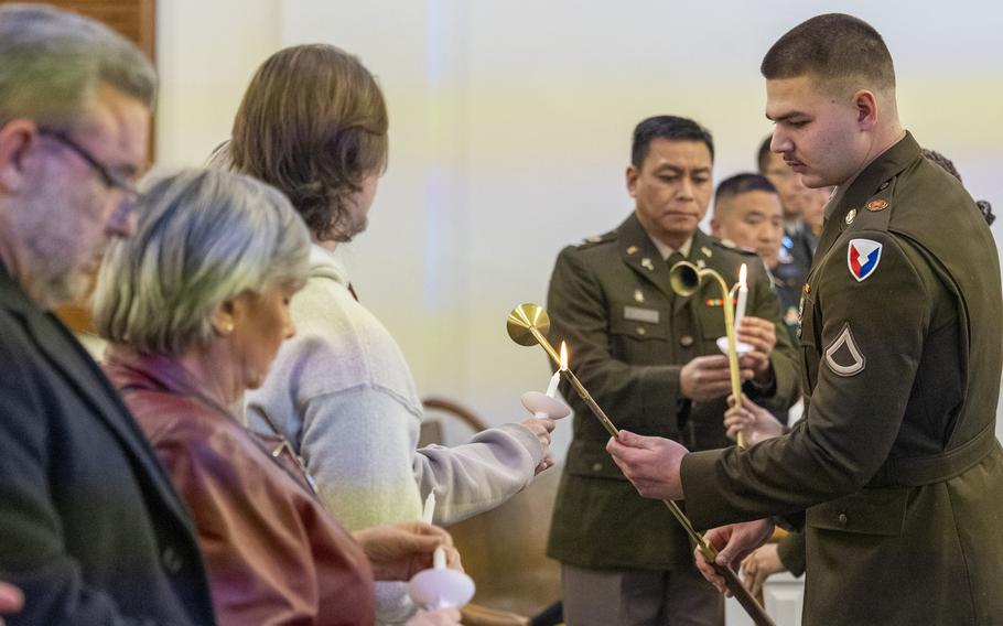 A soldier lights a candle with several others around him.