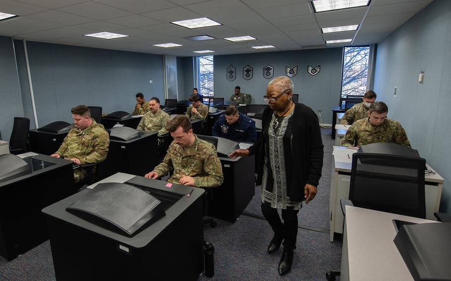 Airmen in uniform sitting in a classroom taking a test.