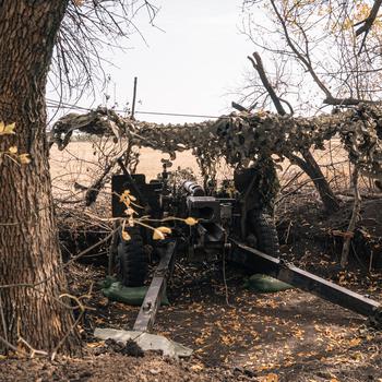 Ukraine soldiers hide a howitzer in the trees.