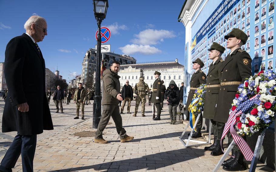 President Joe Biden views Ukrainian soldiers standing in front of a memorial war. 