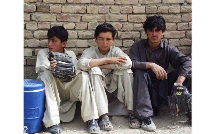Three Afghan boys rest between innings of a baseball game in Orgun-e, Afghanistan. U.S. soldiers have put together two baseball teams with local boys, holding games each Friday.  