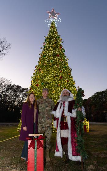 Santa Claus joins others at Arnold AFB in front of the Christmas tree.