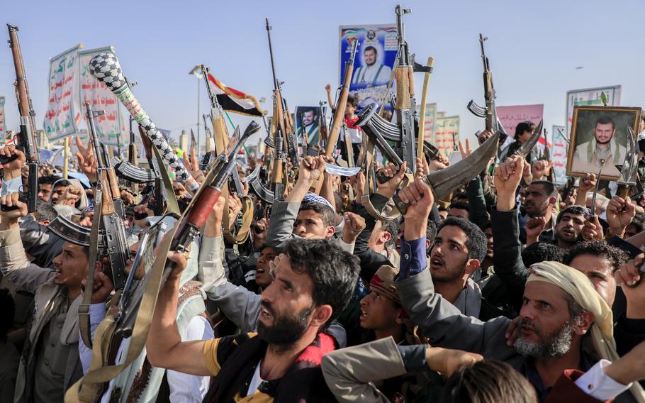 Yemeni rebels raise weapons, posters and flags as they chant during an outdoor rally.