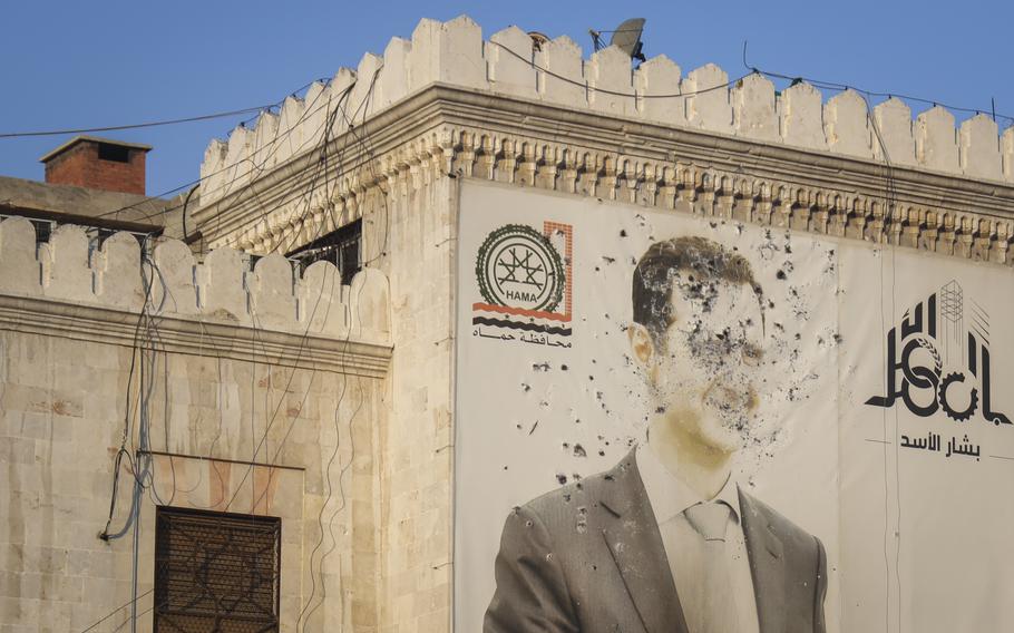 Bulletholes mark a sign depicting Bashar Assad.