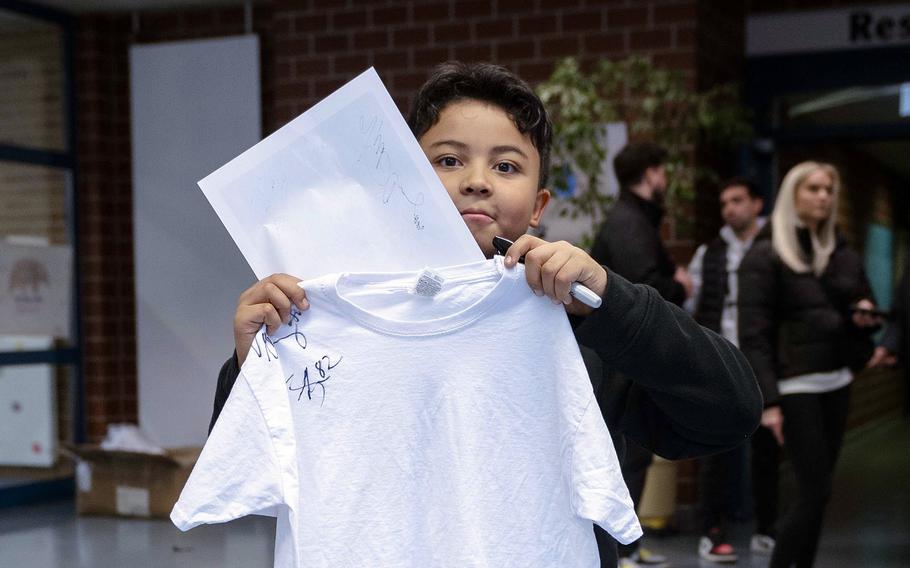 A student shows off his shirt that was signed by former New York Giants players Brandon London and Victor Cruz at Vilseck Elementary School in Germany on Nov. 7, 2024. 