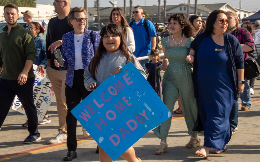 Family and loved ones hold signs during a homecoming ceremony for the USS Stockdale