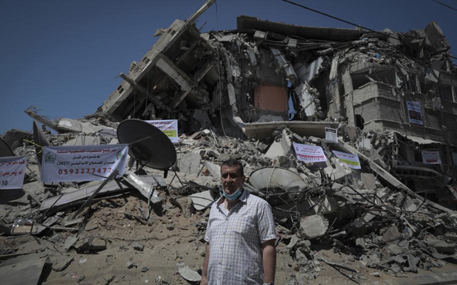 Naji Dwaima, owner of Dwaima’s for Watches, stands on Sunday, May 23, 2021, in front of the rubble of a Gaza City building bombed by Israeli aircraft.