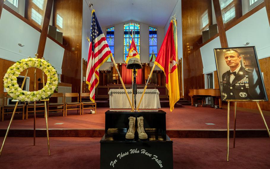 A yellow and white wreath and a photograph of Master Sgt. Justin Sweat flank a  memorial display with flags and boots that reads “For Those Who Have Fallen.”