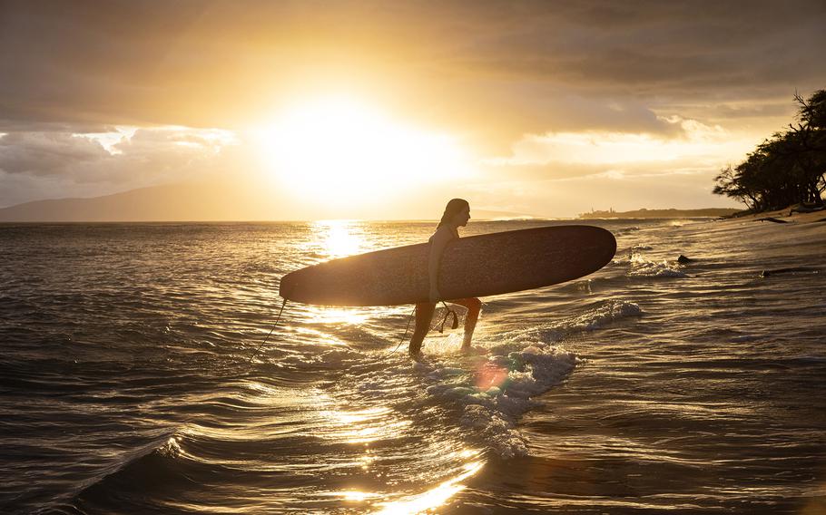 Family and friends of Carole Hartley return to the shore after paddling out from Ukumehame Beach near Lahaina, Hawaii. 