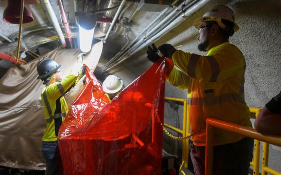 Workers with Joint Task Force-Red Hill set up protective curtains ...