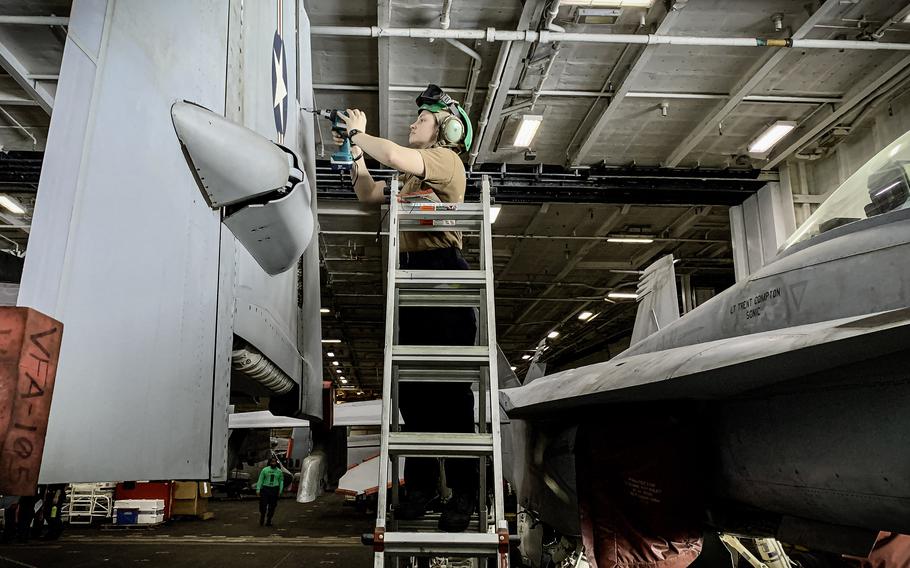 A sailor works on an F/A-18 Super⁤ Hornet in the hangar bay of the aircraft carrier USS Dwight D. Eisenhower on ​March ​20, 2024. The ‍carrier has launched about ‌100 flights⁢ daily ⁢since Dec.​ 31.