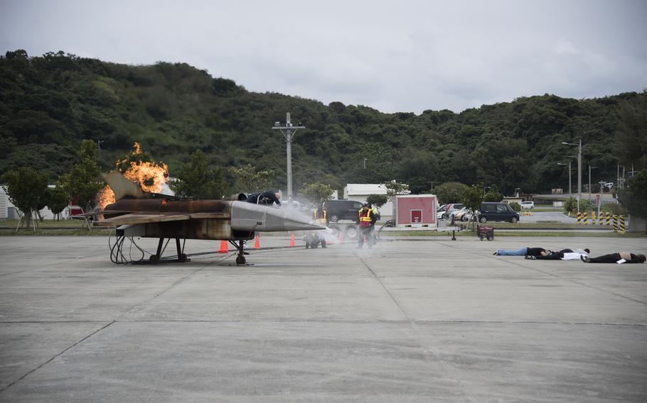 Casualty actors lie around a burning plane mockup during an aircraft mishap exercise.