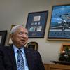 Retired Navy Cmdr. Everett Alvarez speaks during an interview while sitting in front of a picture of a Navy jet and other military memorabilia.