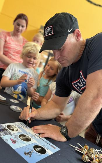 Paralympic champion and Navy SEAL veteran Dan Cnossen signs posters for children at a meet-and-greet at Fort Greely. 