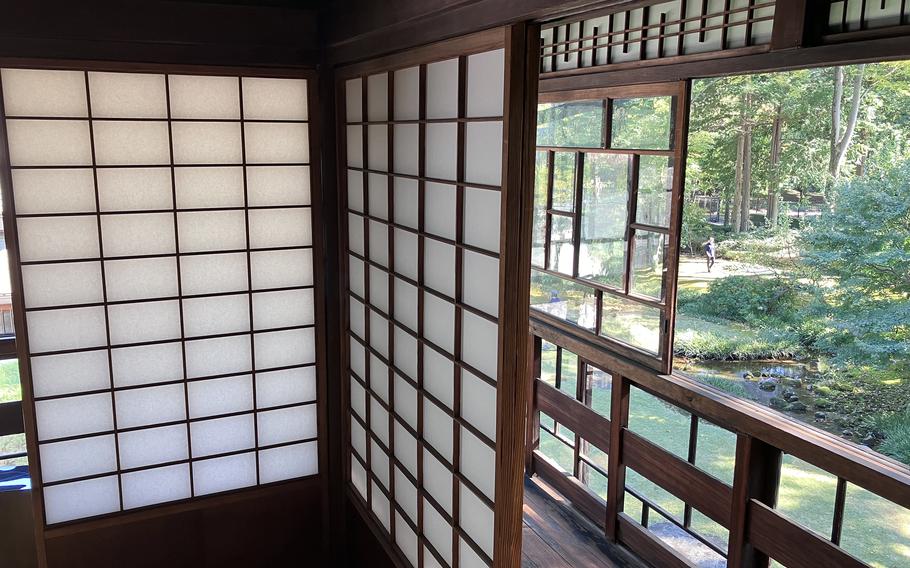 Traditionally Japanese wooden screens with paper panels are seen, and a window reveals a woodsy exterior.