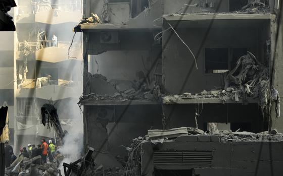 Rescue workers and people gather at the site of an Israeli airstrike that hit central Beirut, Lebanon, Saturday, Nov. 23, 2024. (AP Photo/Hassan Ammar)