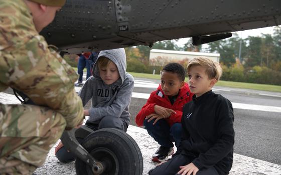 Grafenwoehr Elementary School fourth graders, from left to right, Brycon Smith, Alex Threatt and Leo Oliver, ask soldiers from 2nd Battalion, 227th Aviation Regiment, questions about the Black Hawk helicopter's suspension during the school's annual STEM day at Tower Barracks in Grafenwoehr, Germany, on Oct. 23, 2024.