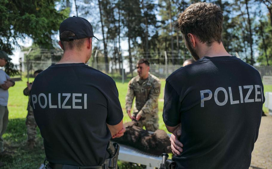 German police officers watch as U.S. Army Capt. Javier Pino, a veterinarian with the Army Veterinary Readiness Activity, Rheinland-Pfalz, explains emergency veterinary first aid procedures at Spangdahlem Air Base, Germany, on June 26, 2024.