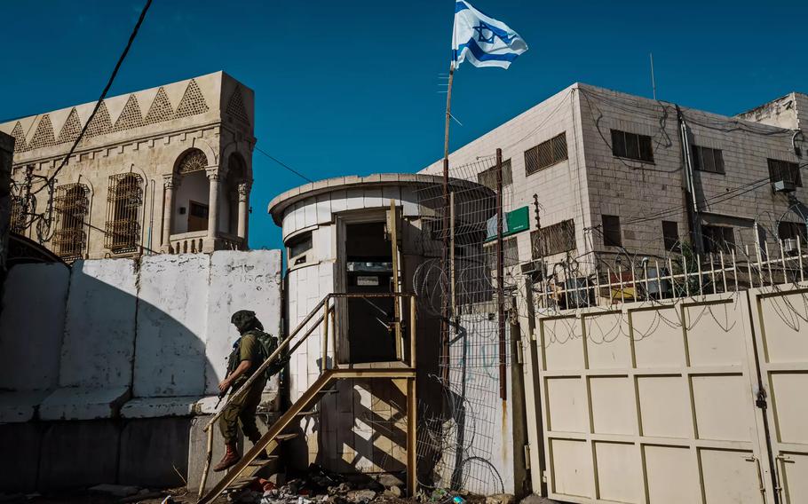 An Israeli soldier steps away from a checkpoint near a fence separating the Palestinian and Israeli sides in Hebron’s Old City.