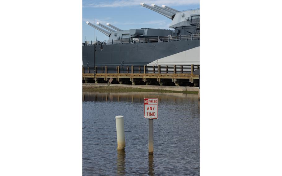 A sign stands in floodwaters in the parking lot of the USS North Carolina National Historic Site.