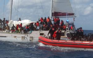 Crewmembers from U.S. Coast Guard Cutter Escanaba distribute personal flotation devices to people from Haiti on board a 30-foot sailing vessel.