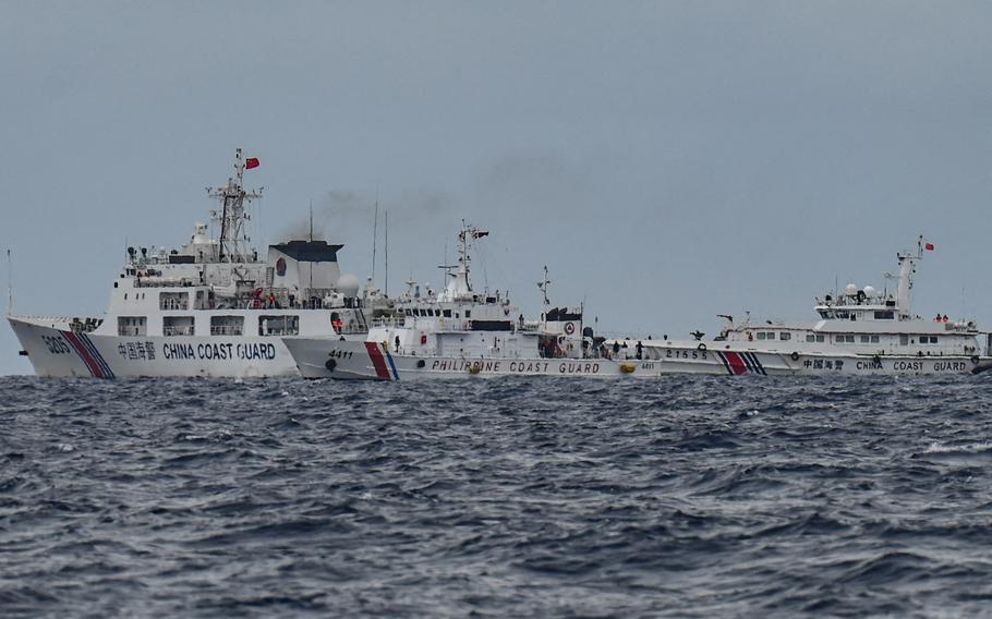 China Coast Guard ships, background left and right, are seen past the Philippine Coast Guard ship BRP Cape Engano, middle, as photographed from the BRP Cabra during a supply mission to Sabina Shoal in disputed waters of the South China Sea on Aug. 26, 2024.