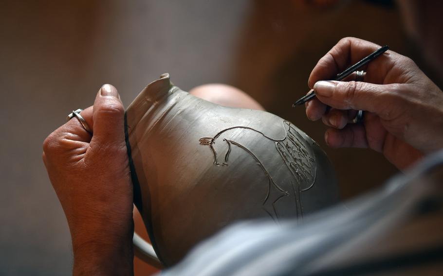 Marie-Line Remmy etches a horse into the soft clay of a pot in the family’s pottery workshop in Betschdorf, France, a small village in the Alsace region known for its gray-blue pottery.