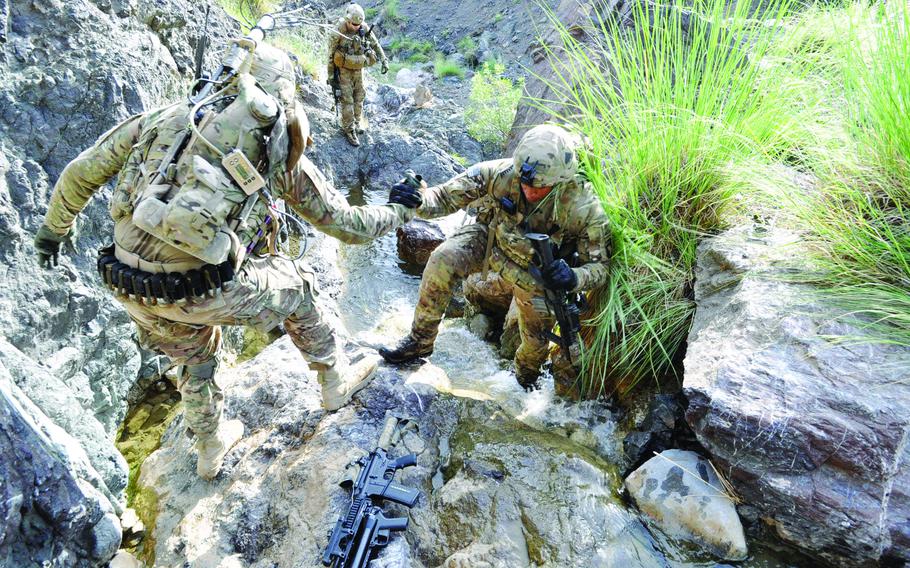 Sgt. Joshua Sutherland, left, helps 2nd Lt. George Fletcher up a waterfall