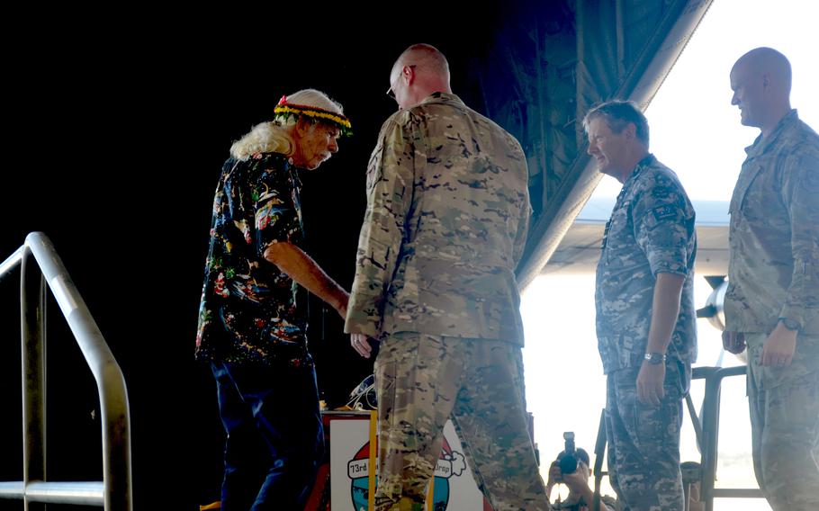 Bruce Best stands next to three service members as they prepare to push a package  onto a C-130J Super Hercules at Andersen Air Force Base.