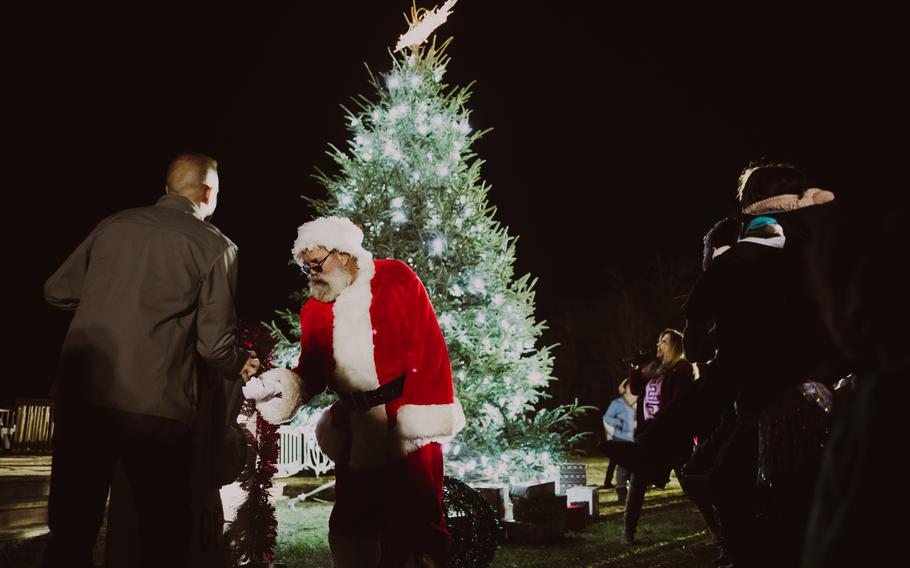 Light from the just-lit Christmas tree shines on Santa Claus and the commander of Marine Corps Air Station New River.