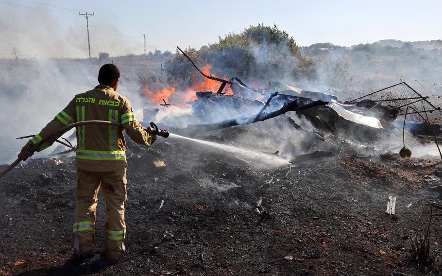 An Israeli firefighter puts out flames in a field after rockets launched from southern Lebanon landed on the outskirts of Kiryat Shmona, on June 4, 2024. Since the outbreak of war between the Palestinian militant group Hamas and Israel on October 7, the Lebanese-Israeli border area has witnessed near-daily exchanges of fire, mainly between the Israeli army and Hamas ally Hezbollah. 