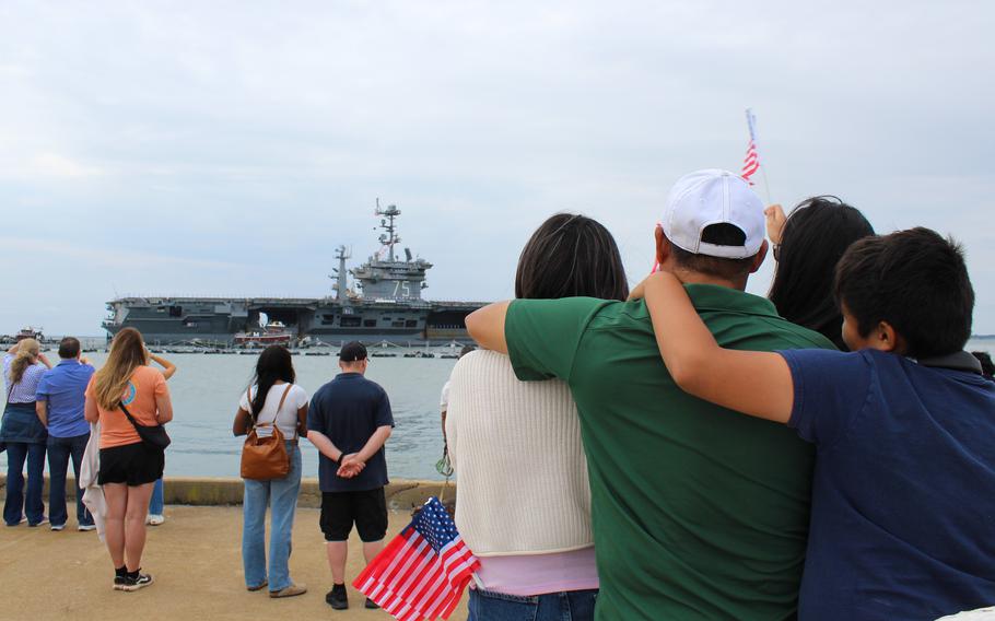 The Morales family clings to each other and waves American flags as the USS Harry S. Truman