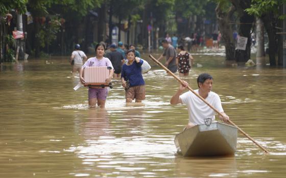 People carrying belongings wade in a flooded street in the aftermath of Typhoon Yagi, in Hanoi, Vietnam on Thursday, Sep. 12, 2024. (AP Photo/Hau Dinh)