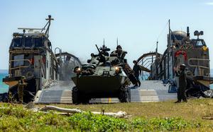 An armored vehicle disembarking a landing craft.