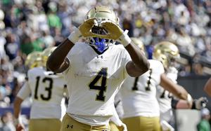 A Notre Dame football player holds up a heart sign with his hands.