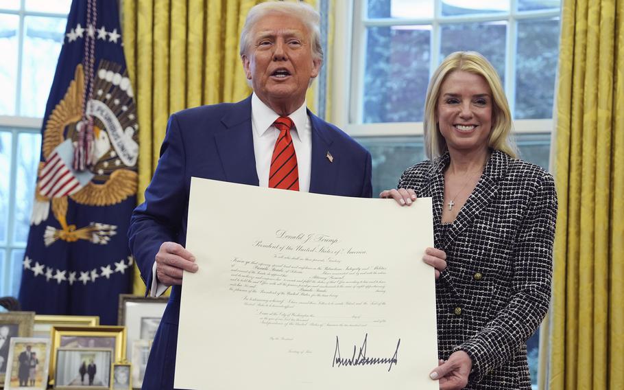 President Donald Trump presents Attorney General Pam Bondi with a document, after she was sworn in by Supreme Court Associate Justice Clarence Thomas.