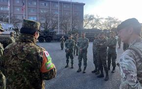 Philippines marines stand in a small group listening to a Japan Ground Self-Defense Force member.