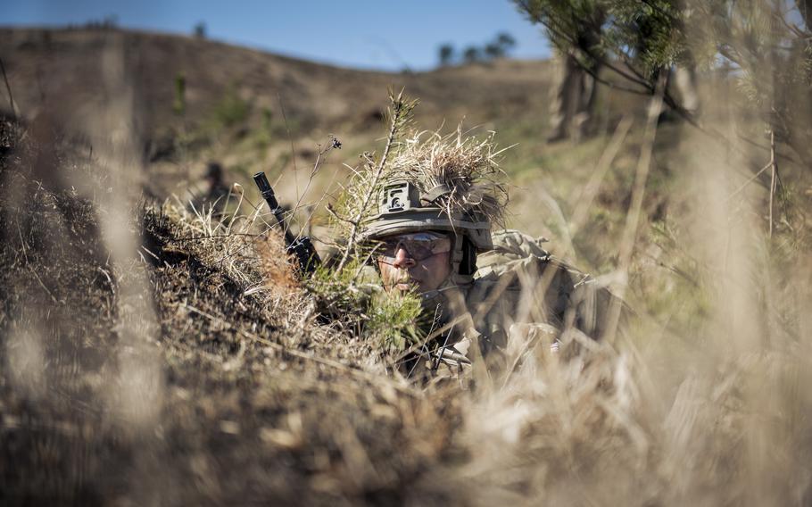 A cadet in camo take cover in a trench