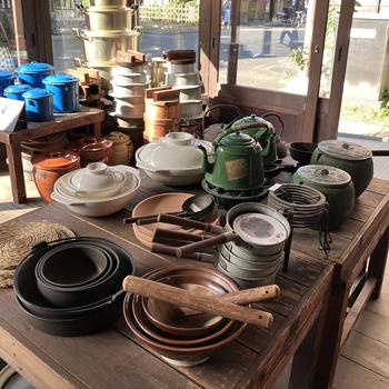 Stacks of bowls and plates are displayed on a shop counter near a window.