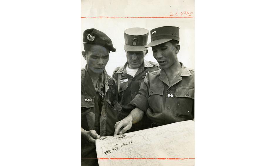 Army Maj. Robert M. Campbell (center) sector advisor for Vietnamese troops operating in the Vinh Long Province, confers with two Vietnamese officers