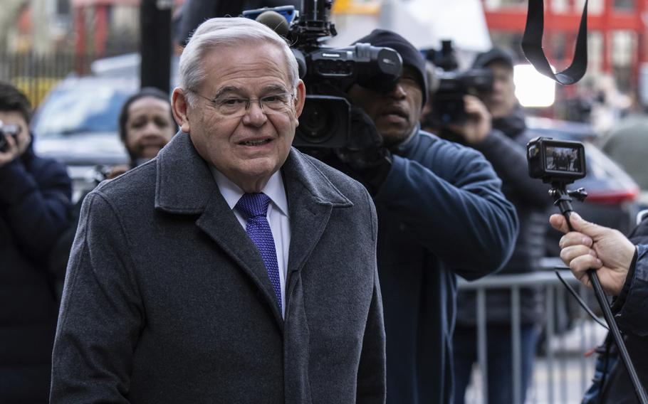 A man with gray hair and glasses outside a courthouse with a TV cameraman behind him.