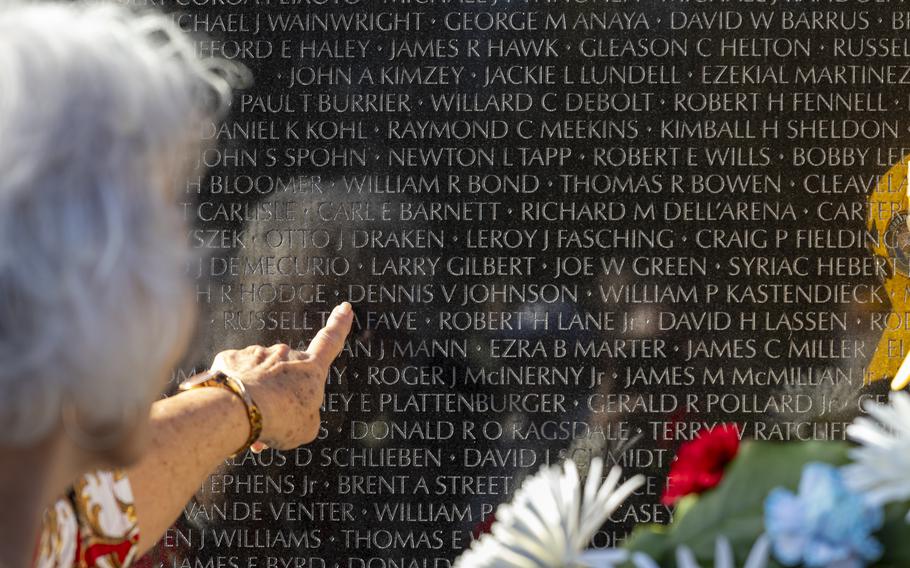 A woman points at a name on the Vietnam memorial wall.