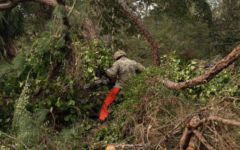 A Georgia Army National Guard soldier uses a chainsaw to clear trees and branches knocked down by Hurricane Helene.